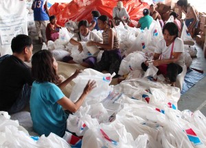 Pantawid Pamilyang Pilipino Program Parent Leaders (foreground) pack rice for the armed conflict and flooding evacuees in Zamboanga City