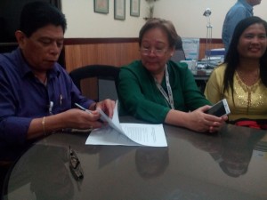 DSWD-Field Office X Asst. Director for Operations Aldersy Mumar Dela Cruz signs the agreement that outlines the provision of rice aid to Bukidnon farmers affected by El Nino while Rebecca Pacquiao (right), representing the farmers group, beams as she looks on.