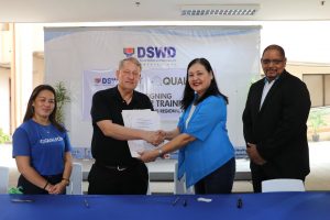 DSWD Regional Director Ma. Evelyn B. Macapobre and Qualfon Cebu Site Director Steve Brown shake hand as a gesture to further seal the partnership of the two agencies.  Also in the photo are Qualfon Dumaguete Site Director David Jackson and Qualfon Education and Community Relations Director Joslyn B. Canon.