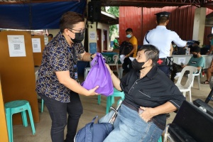 A social worker of the Department of Social Welfare and Development (DSWD) distributes a gift pack to a person with disability client at the DSWD Central Office.