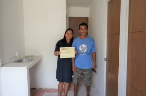 The Teves couple shows their Certificate of Completion, Acceptance, and Occupancy for their new house built through the Core Shelter Assistance Program of the Department of Social Welfare and Development.