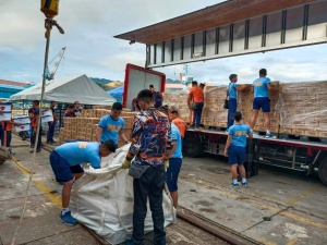 Volunteers from the Philippine National Police unload boxes of family food packs delivered by the winged-van of the United Nations-World Food Programme (UN-WFP).